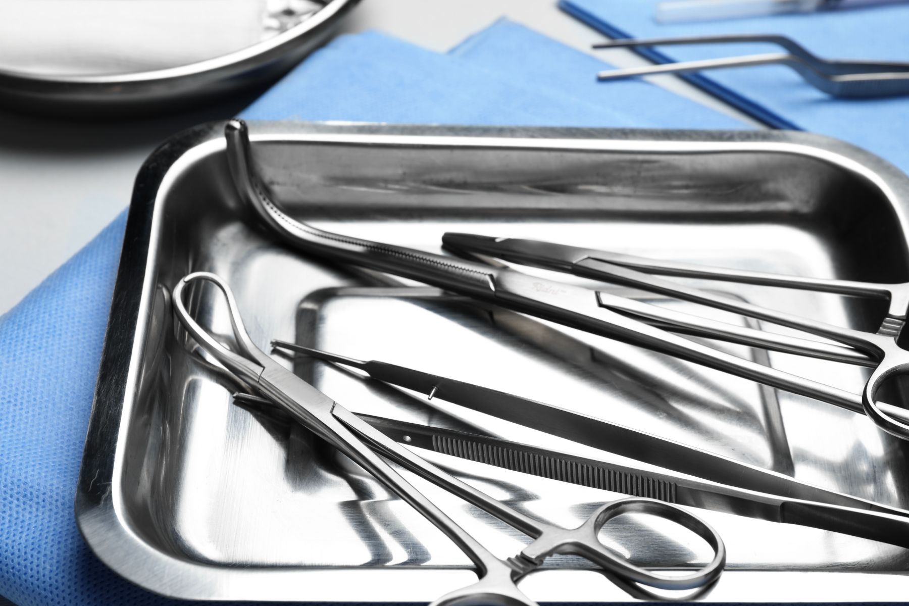 Stainless steel tray of metal clamps and forceps on a surgical drape