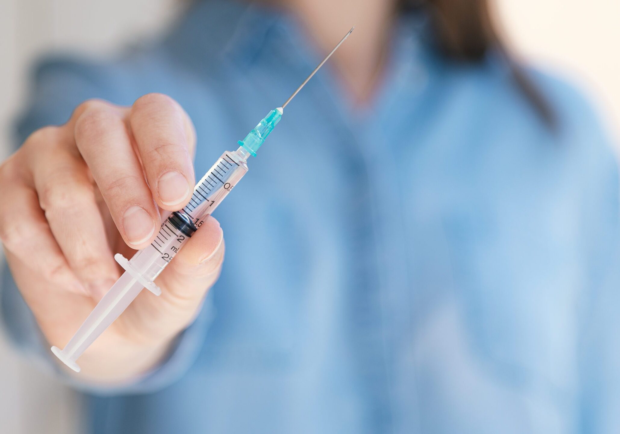 WomanHoldingMedicalInjectionSyringeInHerOutstretchedHandTowards